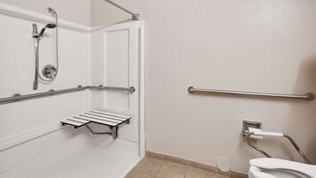 A bathroom with a shower, grab bars, a toilet, and a hand dryer.