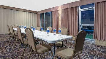 A conference room with a long table, chairs, water bottles, and a carpeted floor.