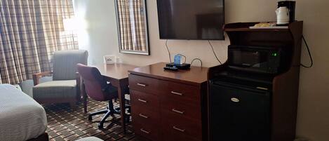 Ein Hotelzimmer mit zwei Betten, einem Schreibtisch mit Stuhl, einem Fernseher, einer Mikrowelle und einer Kaffeemaschine.