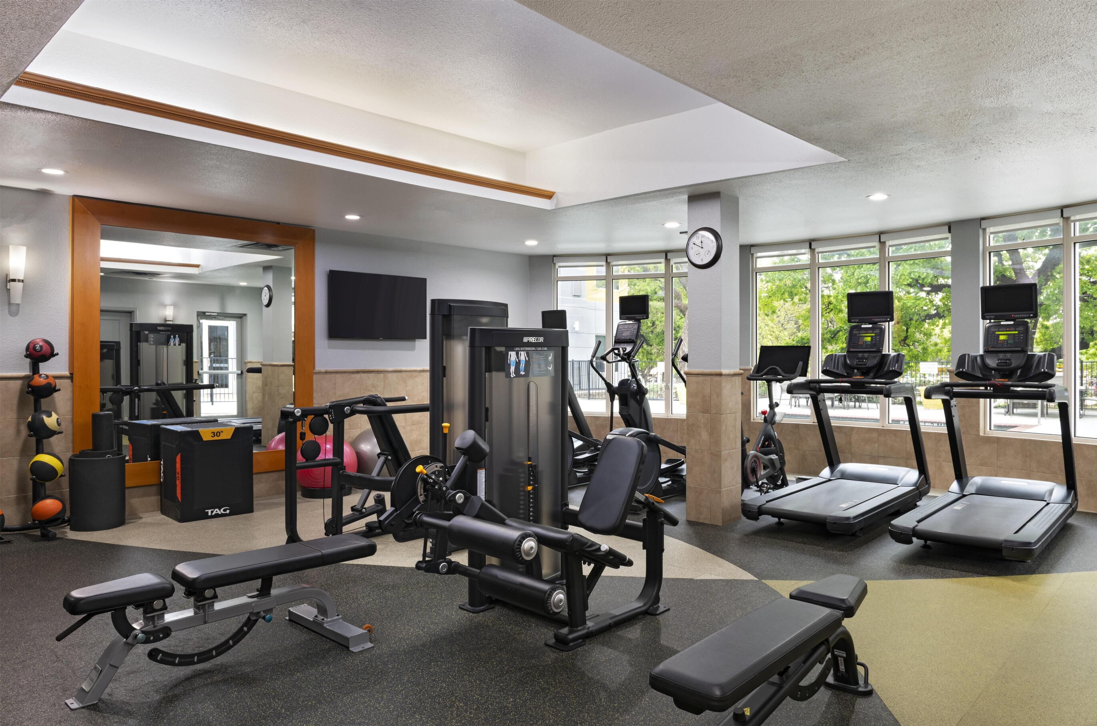 Een fitnessruimte met trainingsapparatuur, loopbanden en een spiegel.