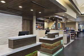 Ein Hotel-Empfangsbereich mit modernem Design, inklusive einer Rezeption, einer Minibar und einer Sitzecke.