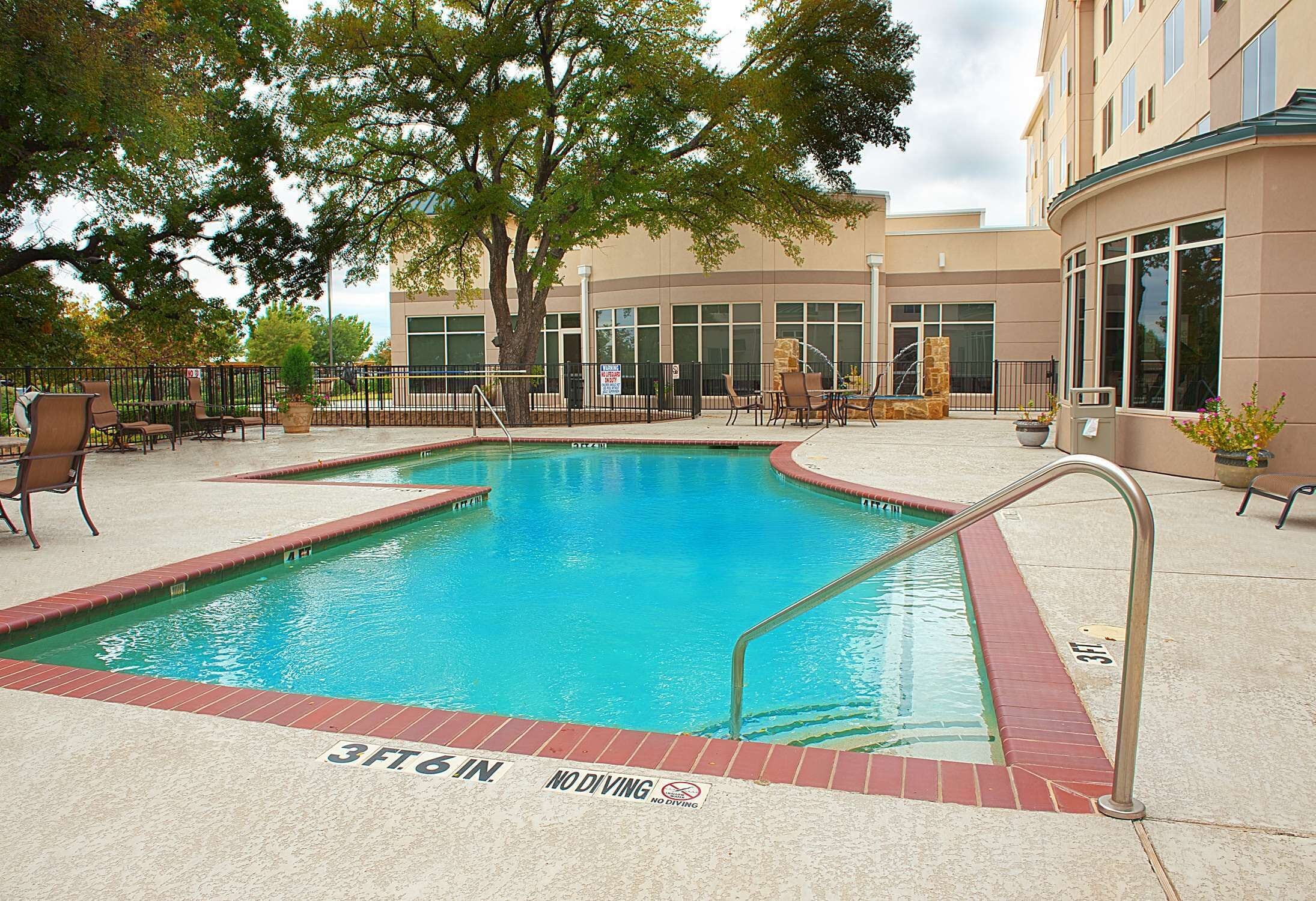 A swimming pool with a 'No Diving' sign, surrounded by lounge chairs and a building in the background.