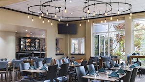 Un restaurant doté de nombreuses tables, de chaises et d’un bar.