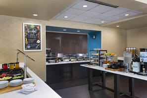 A breakfast buffet with various food options, a clock, and a beverage station.