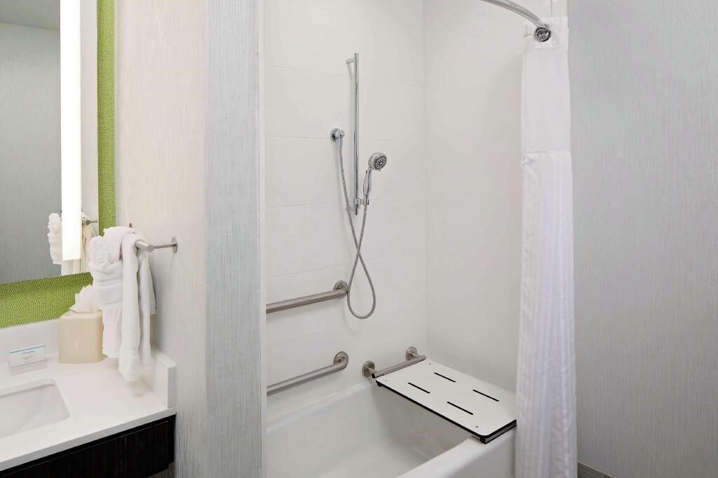 A bathroom with a shower, a sink, and a towel rack.