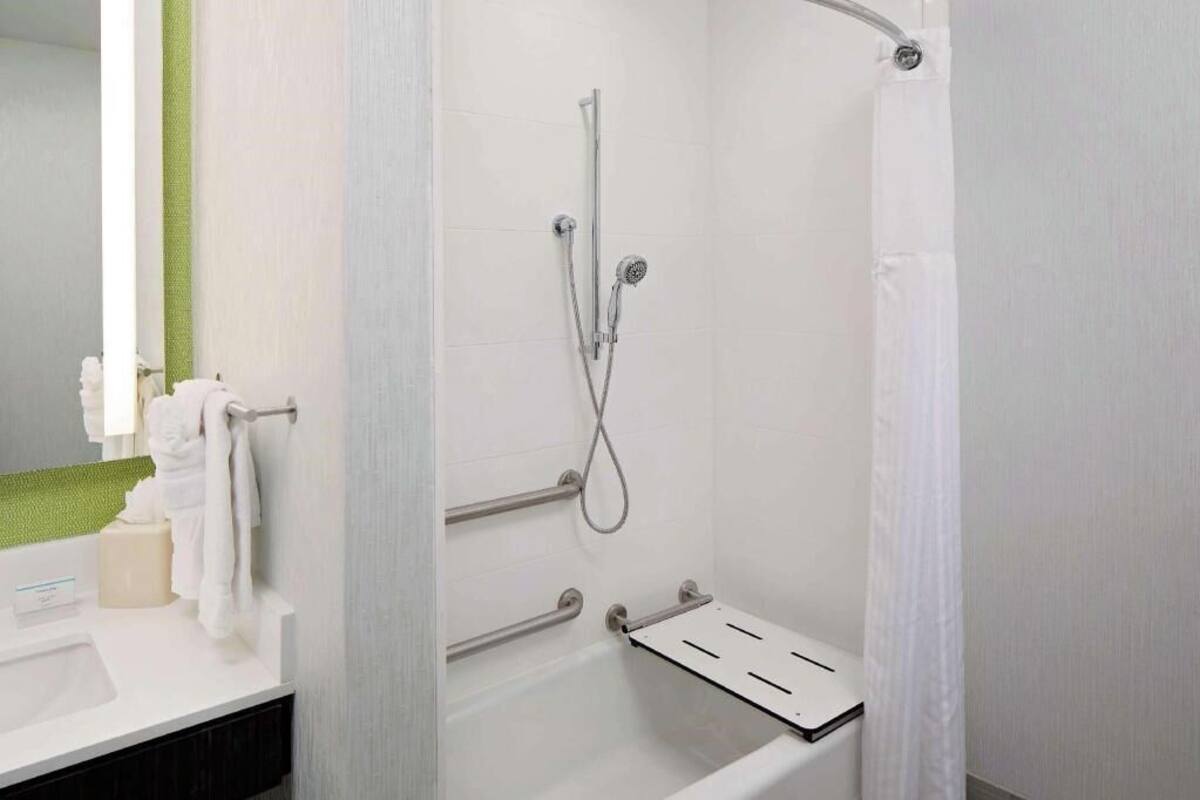 A bathroom with a shower, a sink, and a towel rack.