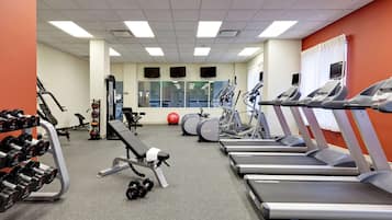 A gym with treadmills, dumbbells, and exercise balls.