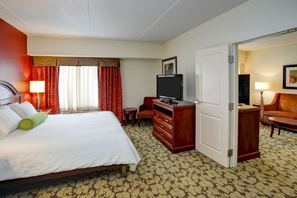 A hotel room with a bed, a television, a desk, and a chair.