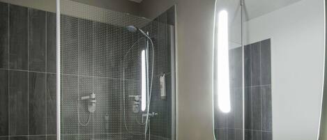 A modern bathroom with a shower, a sink, and a mirror.