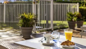 A breakfast table with a croissant, a cup, a glass of water, and a glass of orange juice. - ibis Tarbes Odos (Odos)