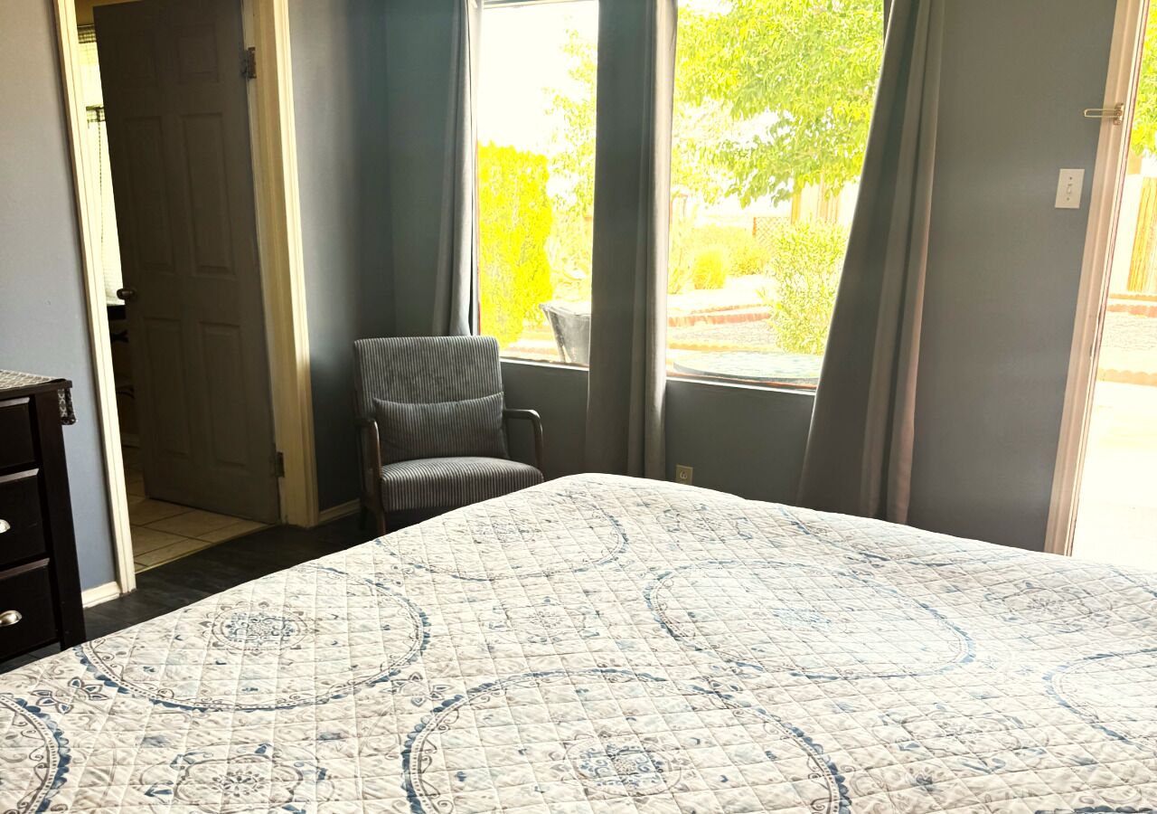 A bedroom with a bed, a chair, a window, and a door.