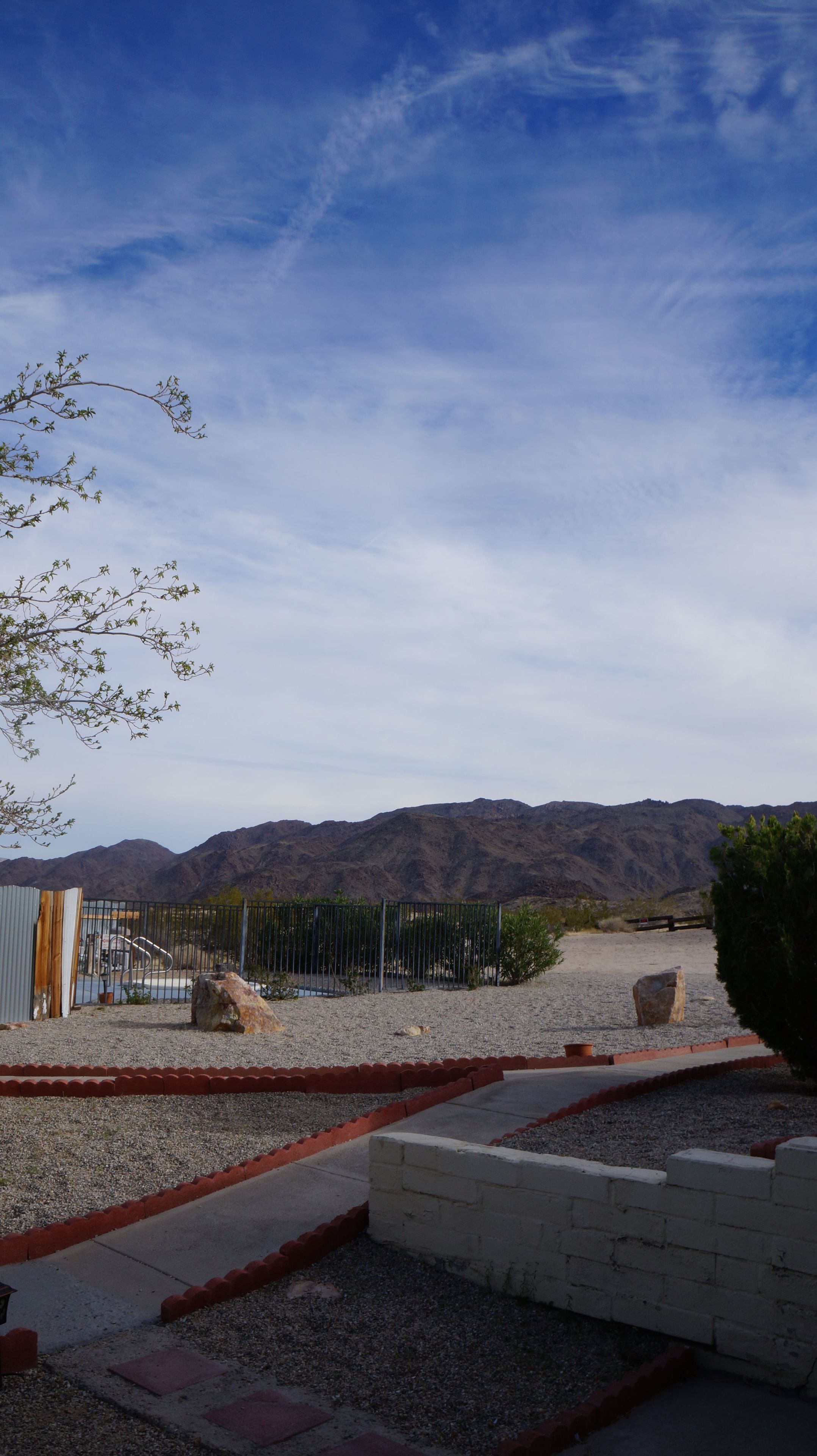 A parking area with a gravel surface, a metal fence, and a building with a corrugated metal exterior.