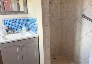 Une salle de bain Ă©quipĂ©e dâun lavabo, dâun miroir et dâun espace douche.