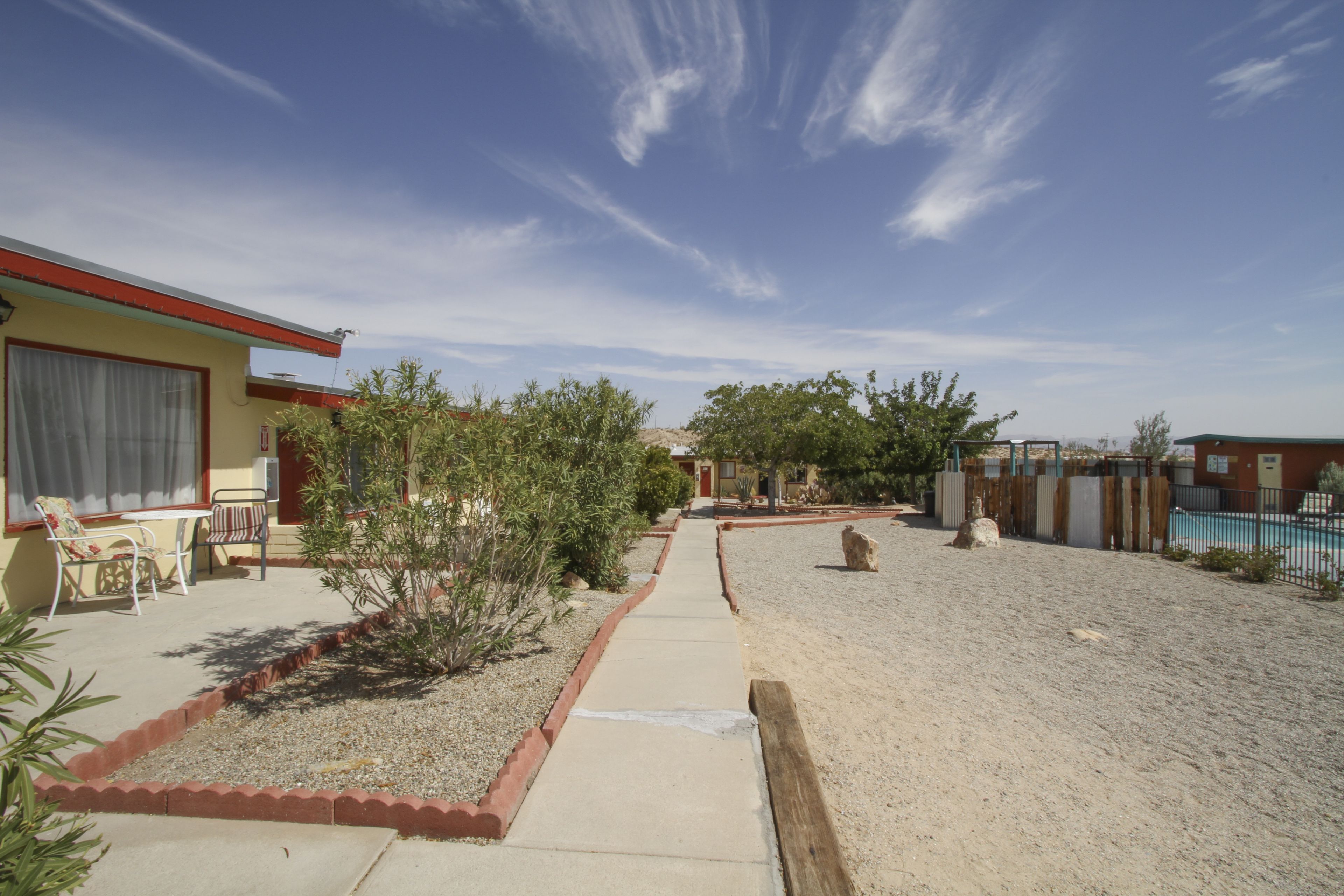 A residential area with a paved walkway, a pool, and a building with a red roof.