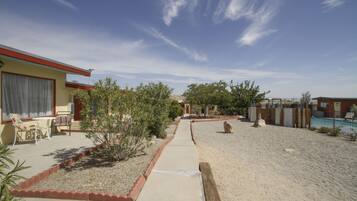 A residential area with a paved walkway, a pool, and a building with a red roof.