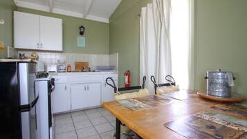 A kitchen with white cabinets, a refrigerator, a coffee maker, and a table with a placemat.