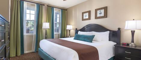 A hotel room with a bed, two bedside lamps, a ceiling fan, a nightstand, and a dresser.