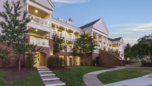 A large, multi-story building with a central courtyard, featuring balconies and a brick facade. - Club Wyndham Governor’s Green (Williamsburg)