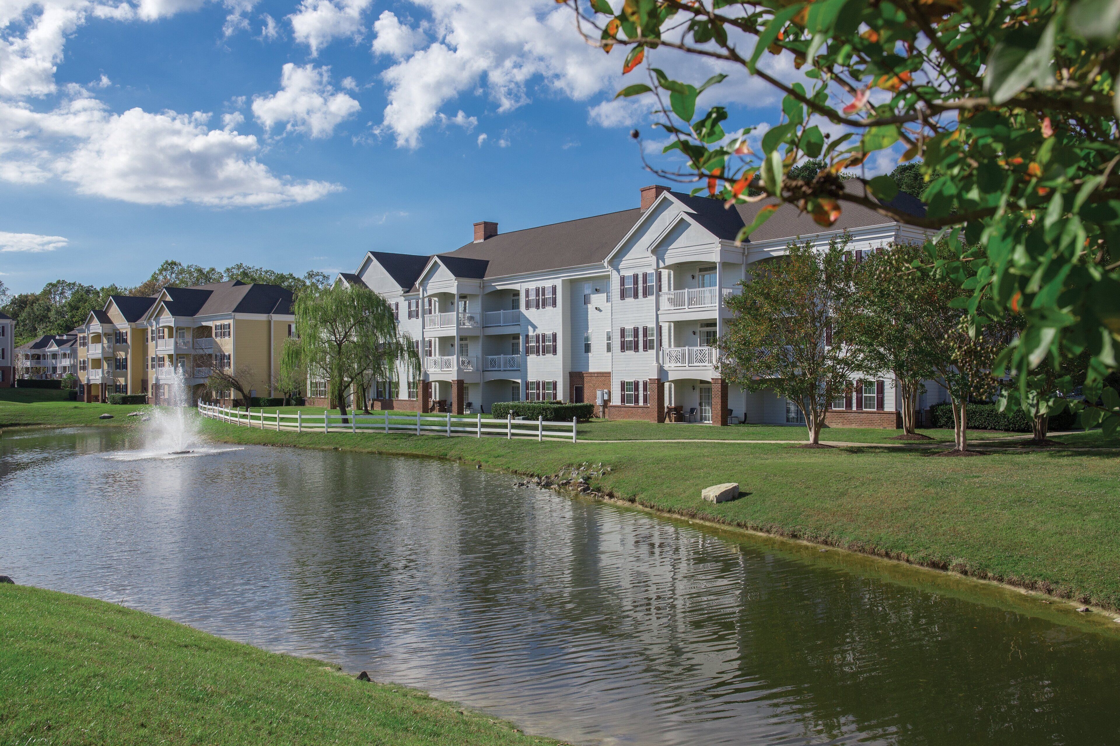 A residential area with a pond and a white fence.
