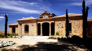 A stone building with a clock tower, arched doorways, and a tiled roof.