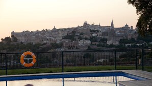 A swimming pool with a lifebuoy and a fence, overlooking a cityscape with historic buildings. - Hotel Cigarral El Bosque (Toledo)