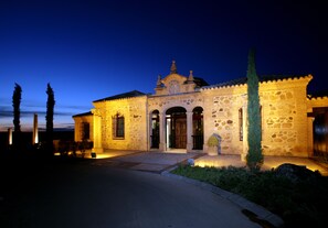 A stone building with a central entrance, arched doorways, and a decorative roof.