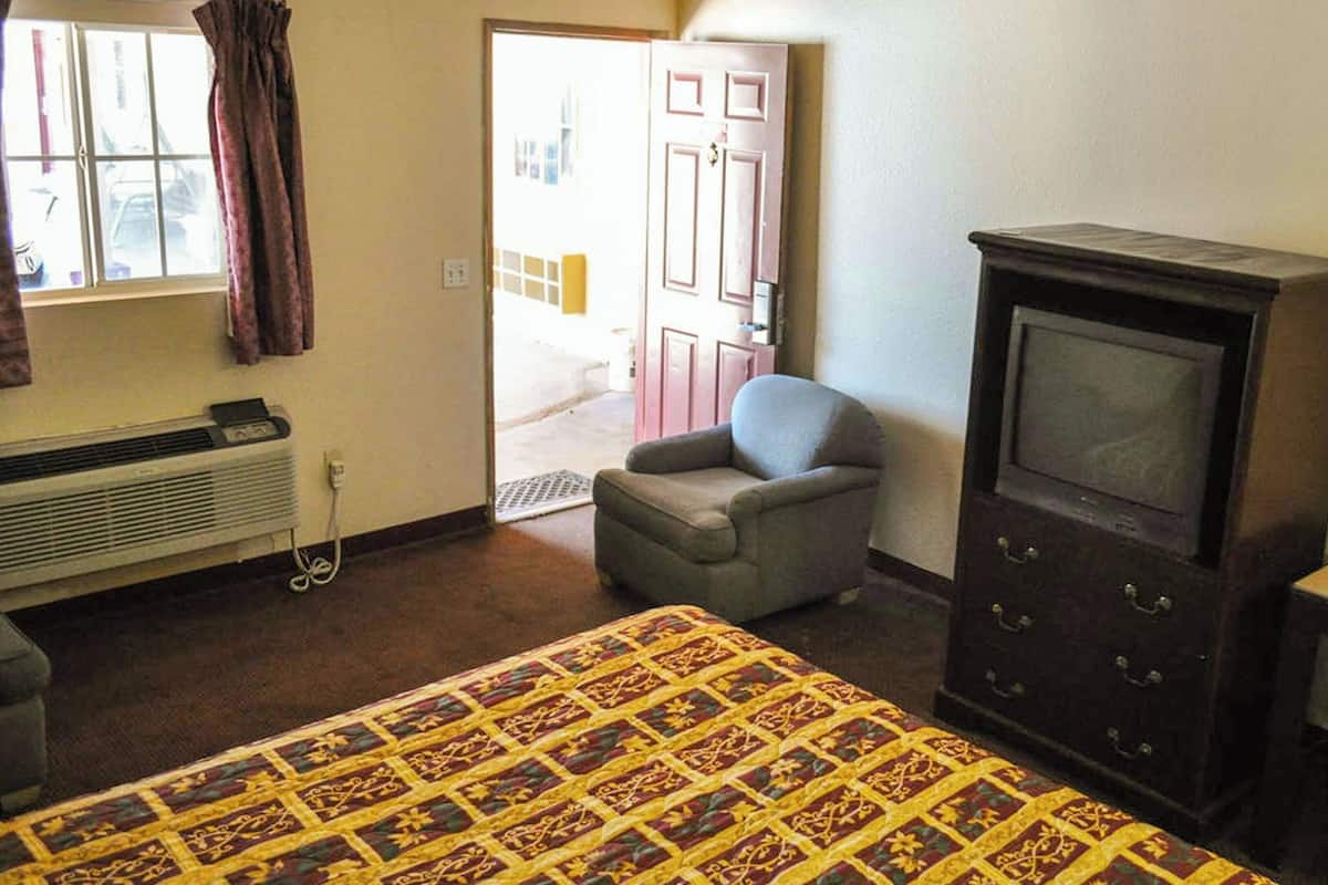 A room with a bed, a chair, a television, and a wardrobe.