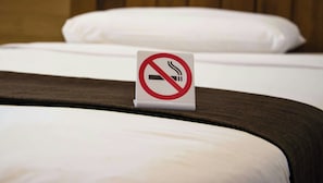 Una cama con un cartel de prohibido fumar en la cabecera.
