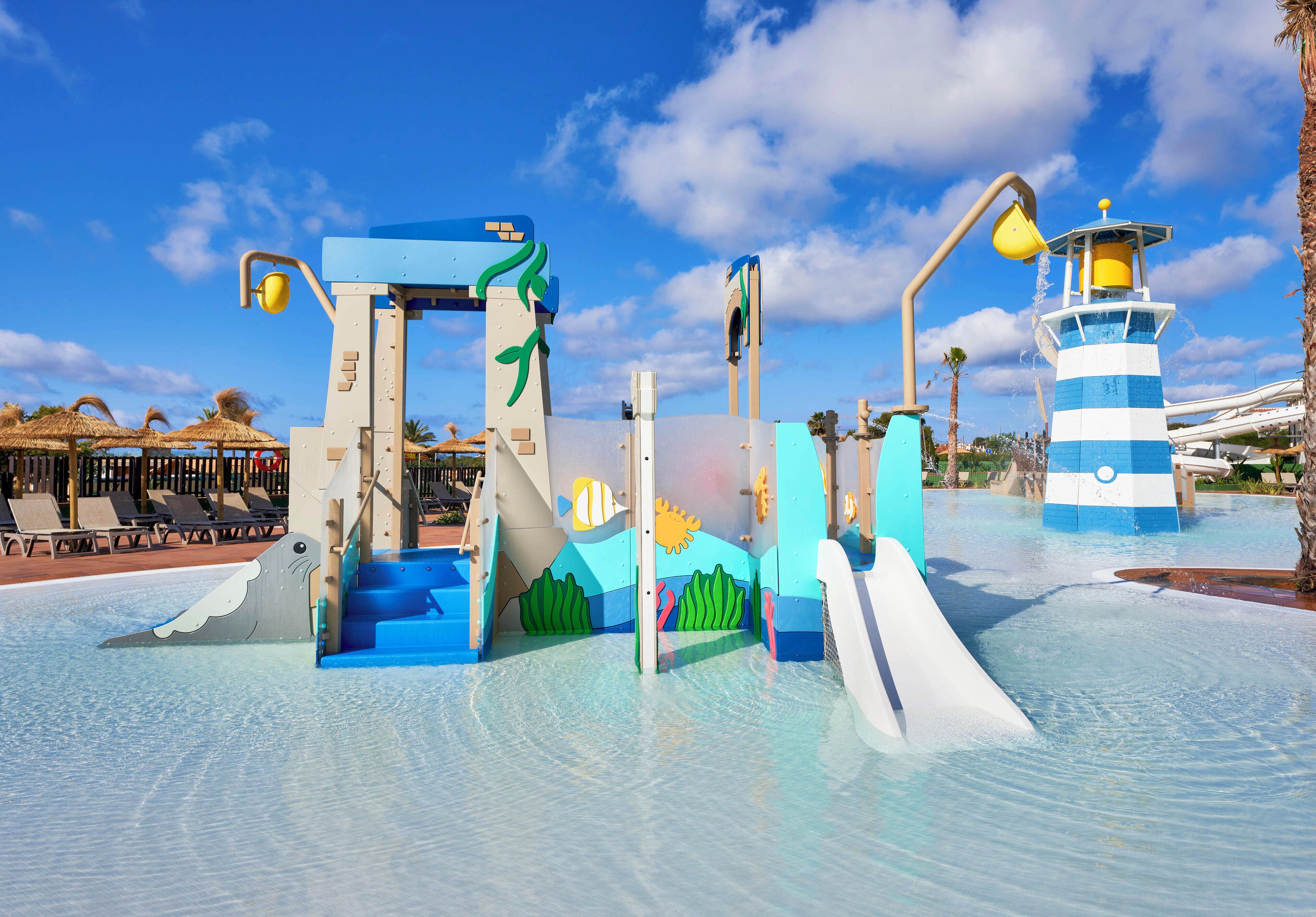 Un parc aquatique avec des toboggans et une structure de jeux sur le thème d’un phare.