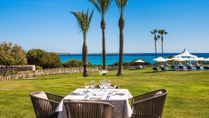 A table set outdoors with a view of the sea and palm trees. - Insotel Punta Prima Prestige Suites & Spa (Sant Lluis)