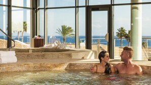 A couple in a hot tub with a view of the ocean and palm trees. - Insotel Punta Prima Prestige Suites & Spa (Sant Lluis)