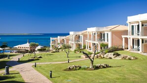 A resort with multiple buildings, a clear blue sky, and a view of the sea. - Insotel Punta Prima Prestige Suites & Spa (Sant Lluis)