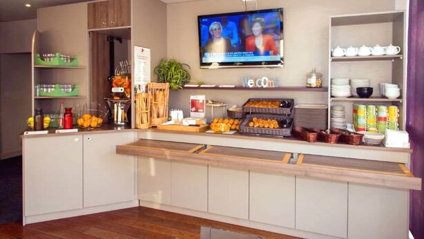 A breakfast bar with a television, shelves with dishes, and a variety of food items.