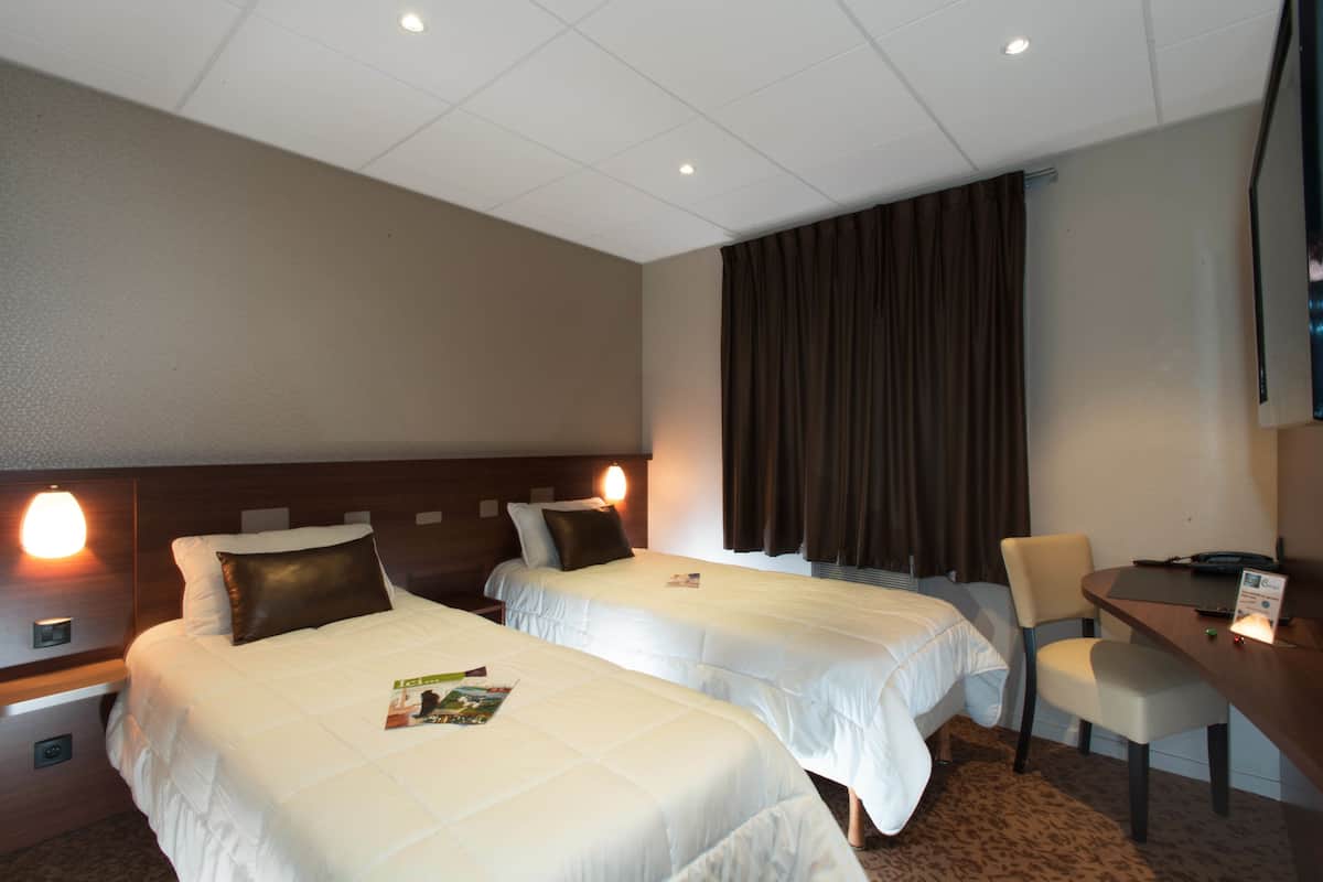 A hotel room with two beds, a desk, a chair, and a television.