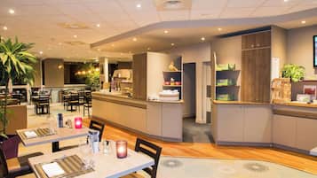 A modern restaurant with a central bar area, multiple dining tables, and a variety of seating options.