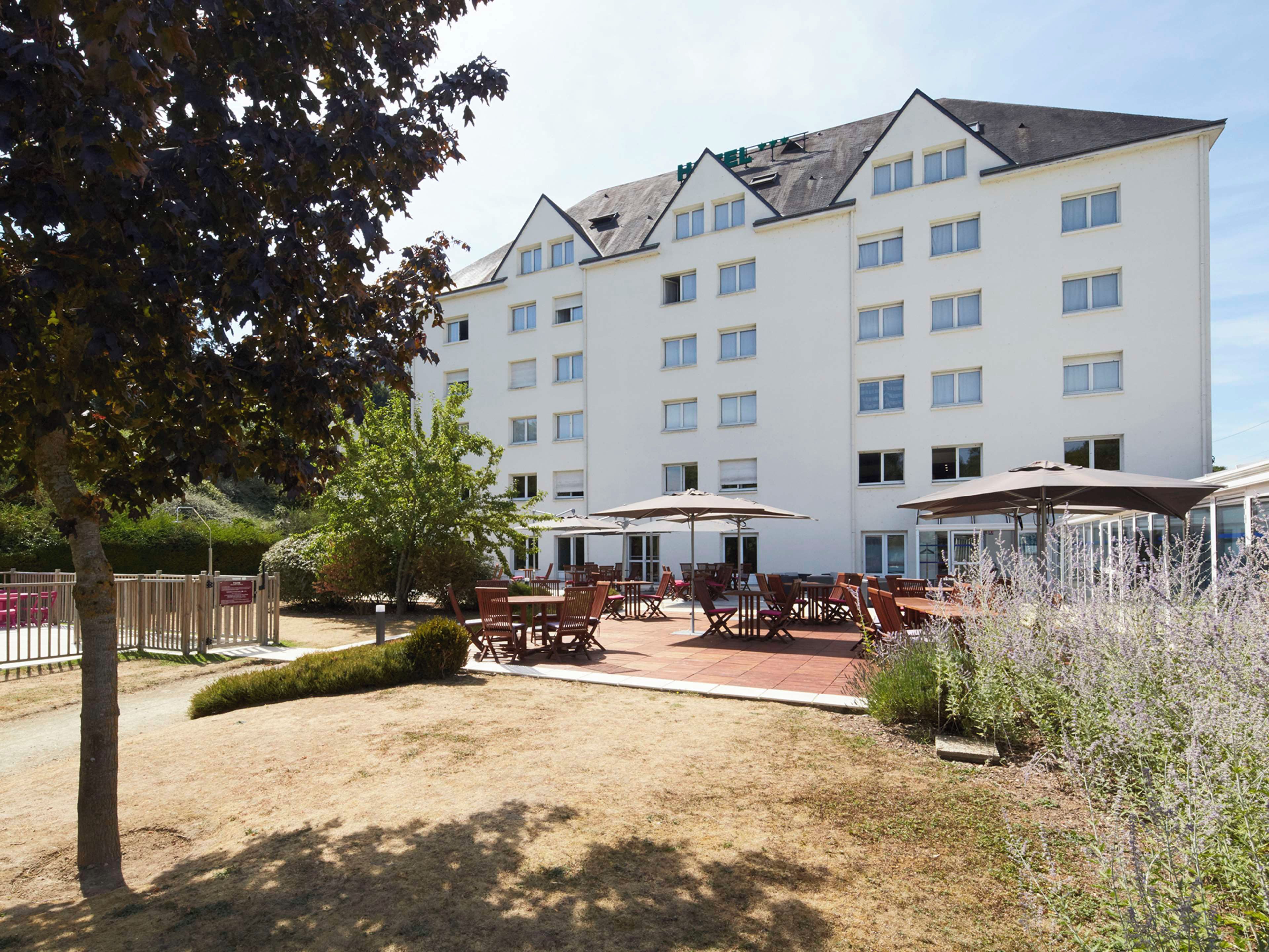 A hotel with multiple floors, outdoor seating, and a fenced garden area.
