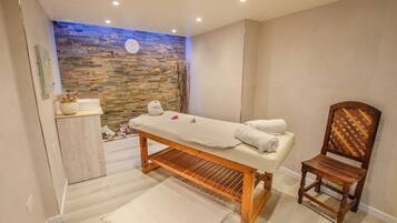 Relax in a serene space with a massage table, comfortable chair, and soothing mosaic wall.