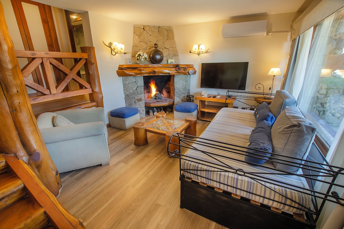 Una sala de estar acogedora con chimenea de piedra, un televisor y un espacio de descanso cómodo.