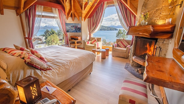 Un dormitorio acogedor con una cama grande, una chimenea y vistas a un lago.