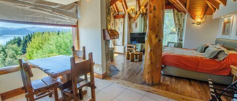 Interior de madera con comedor, cama y vista a un lago.