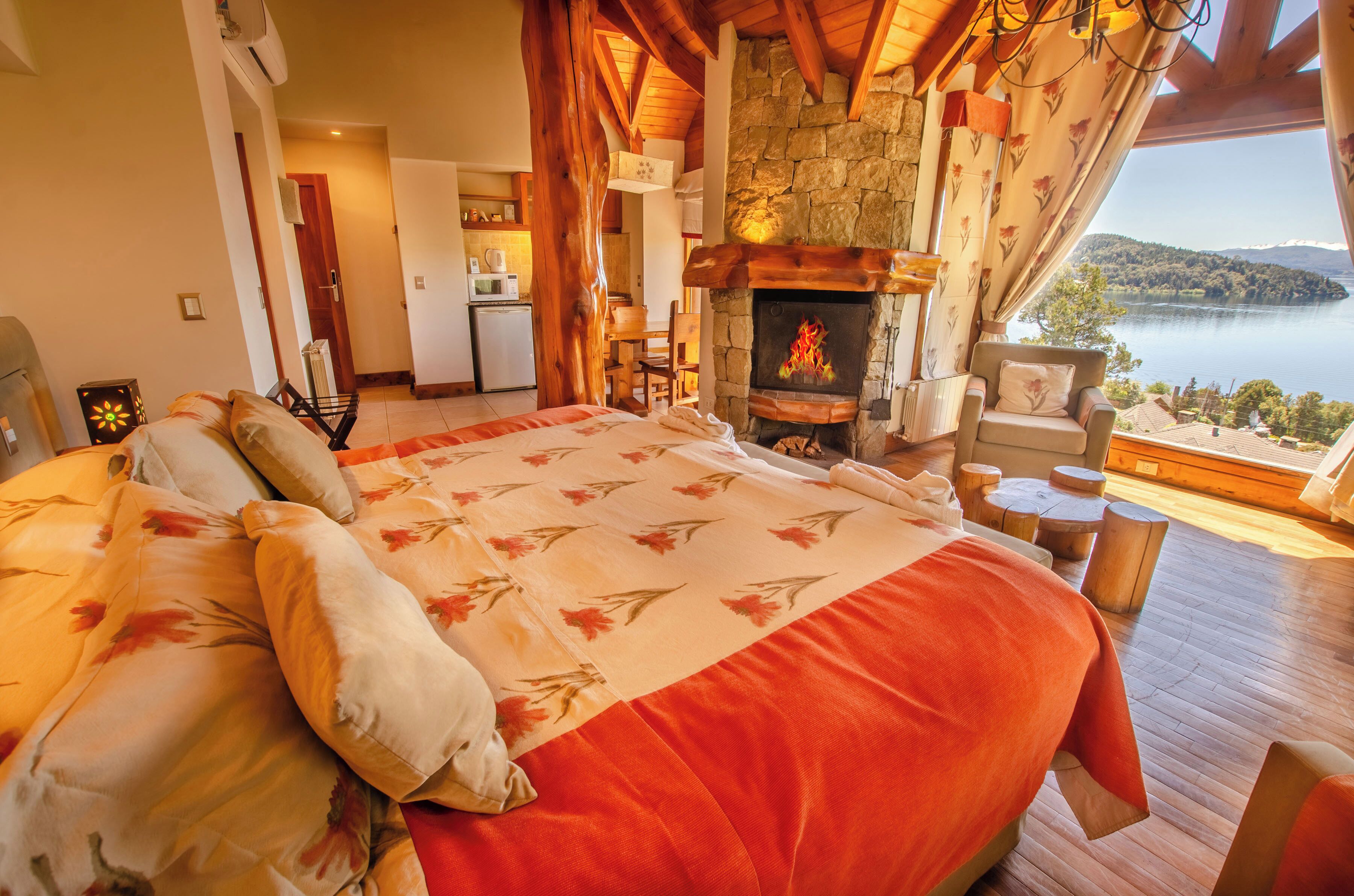 Une chambre avec un grand lit, une cheminée en pierre et une vue sur un lac.