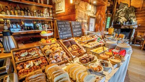 Un bufé con panes, pasteles y frutas variados.