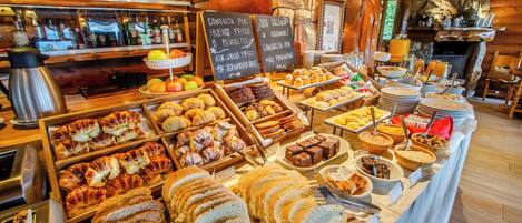 A buffet with various breads, pastries, and fruits.