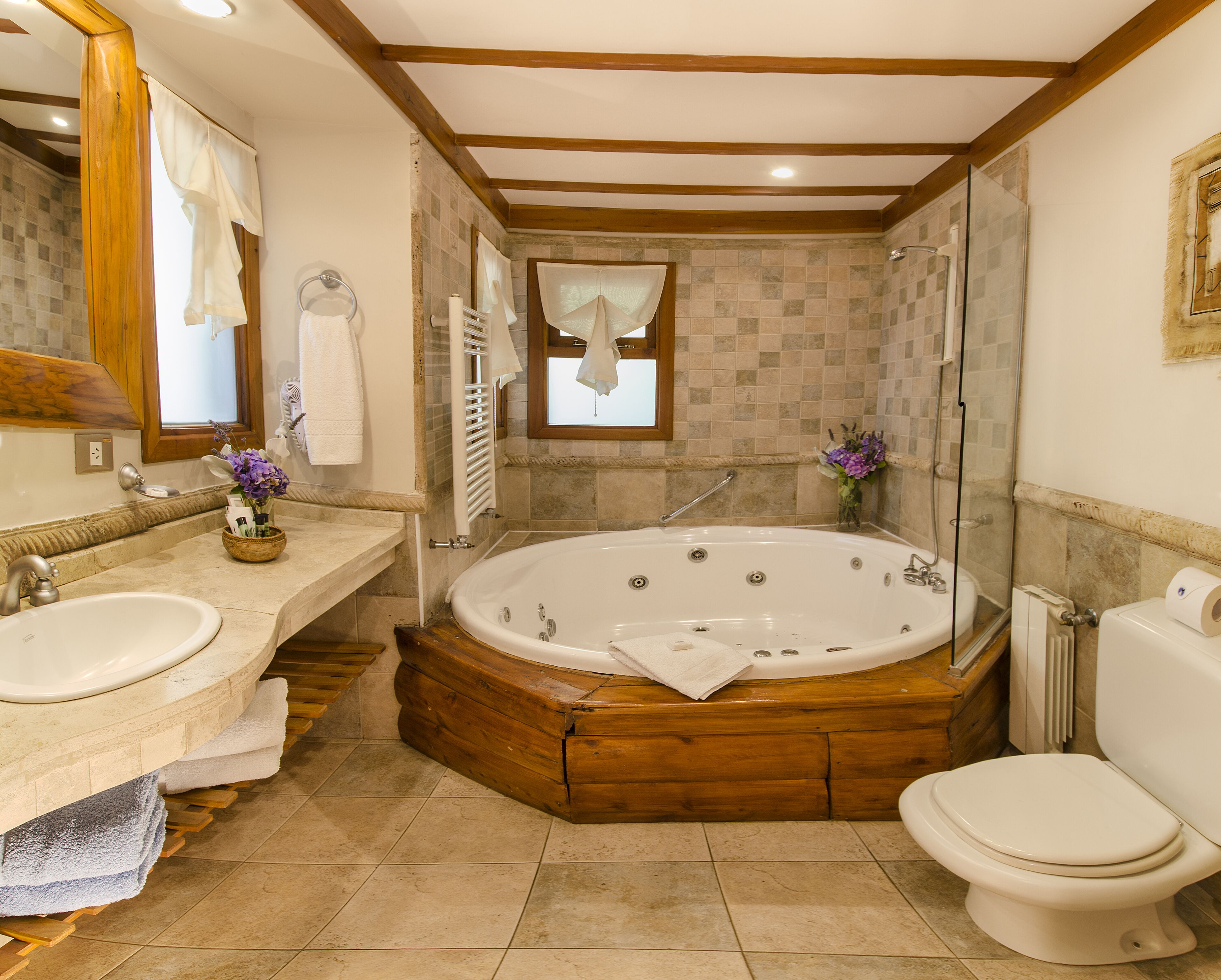 Un baño con una bañera de madera, un lavabo doble y un inodoro.
