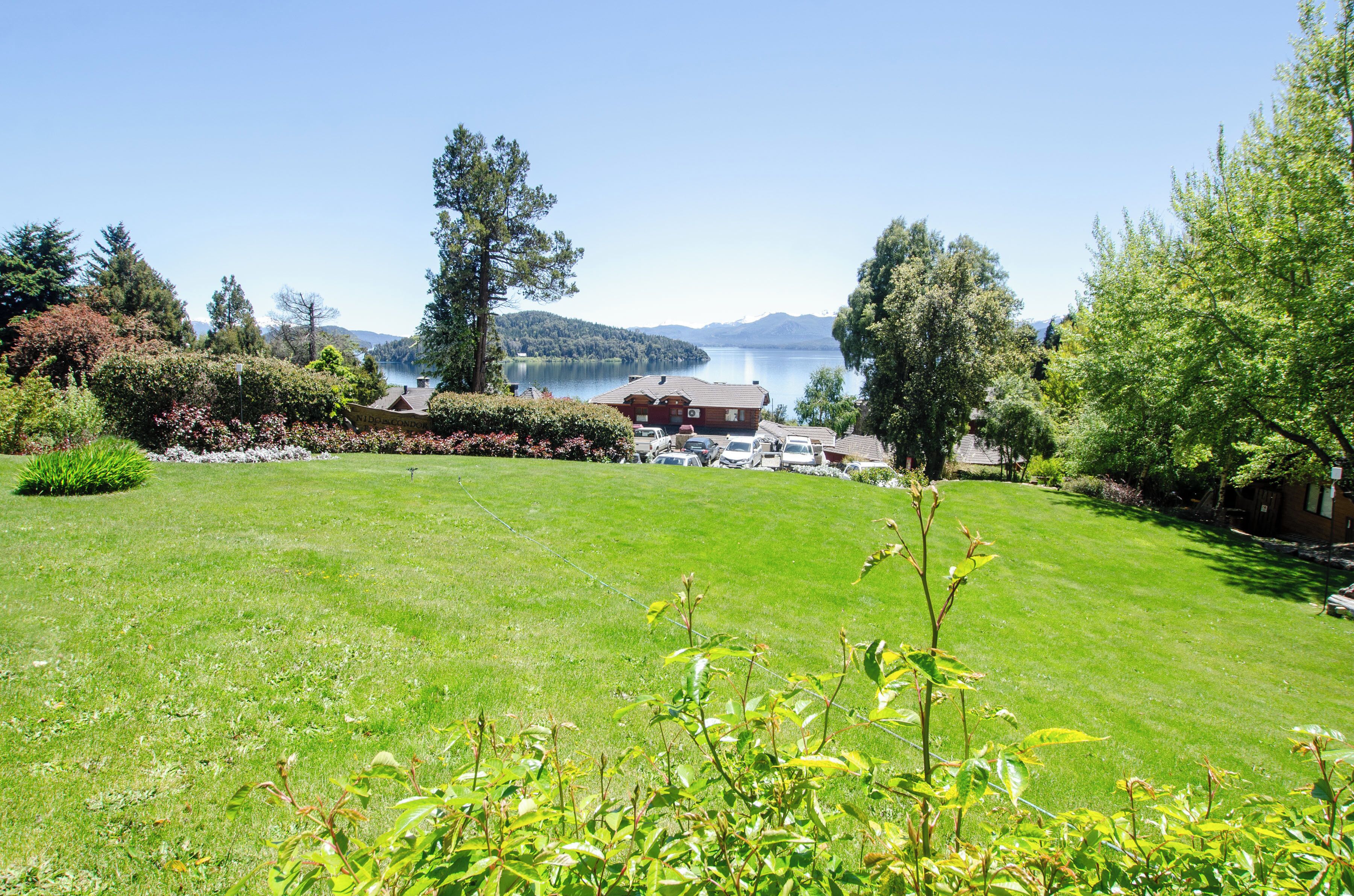 A well-maintained lawn with a view of a lake and mountains in the background.