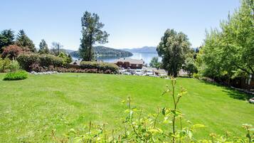 A well-maintained lawn with a view of a lake and mountains in the background.