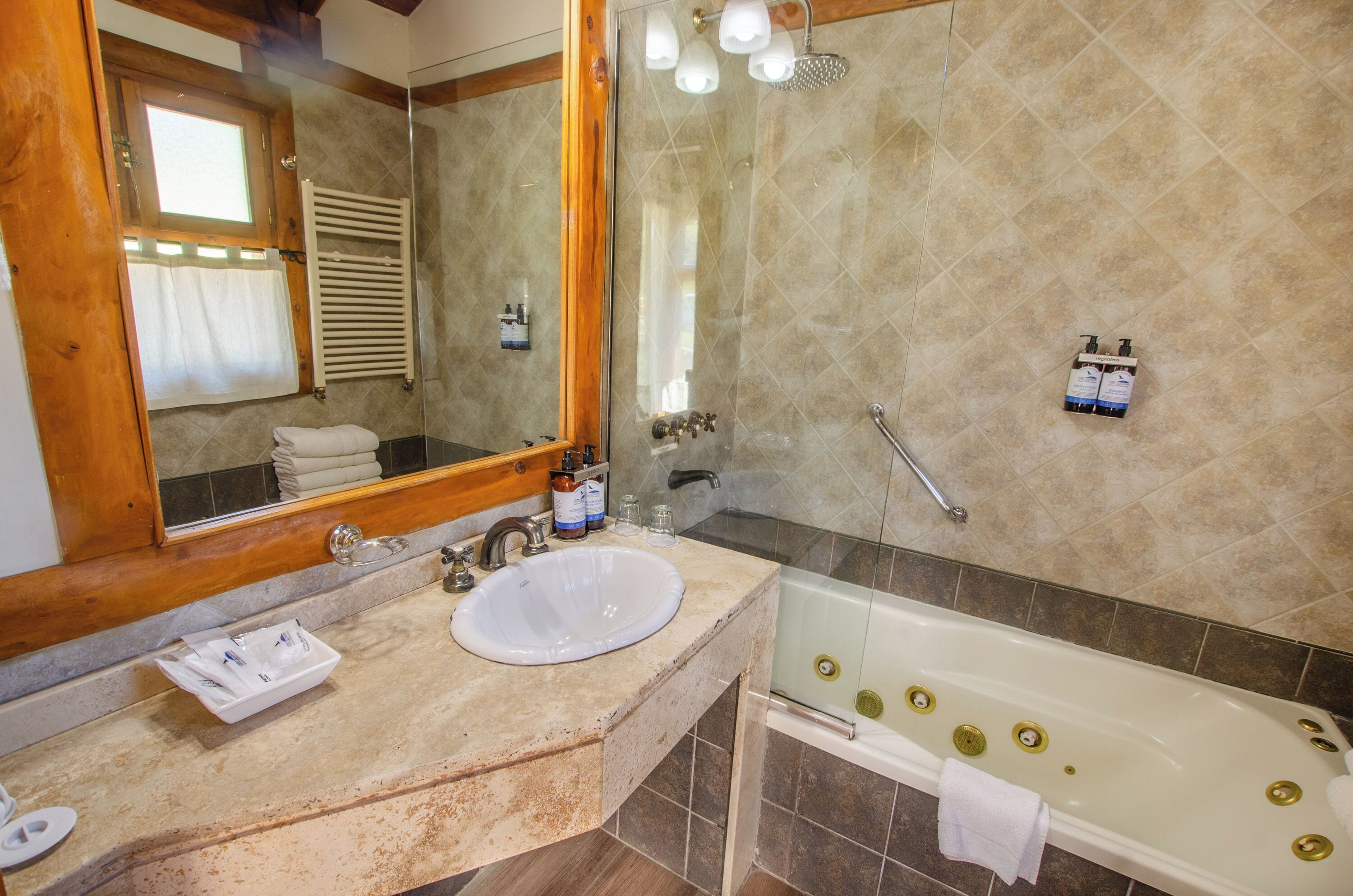 A bathroom with a sink, mirror, and bathtub.