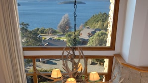 Una sala de estar acogedora con un gran ventanal con vistas a un lago, una chimenea y una araña.