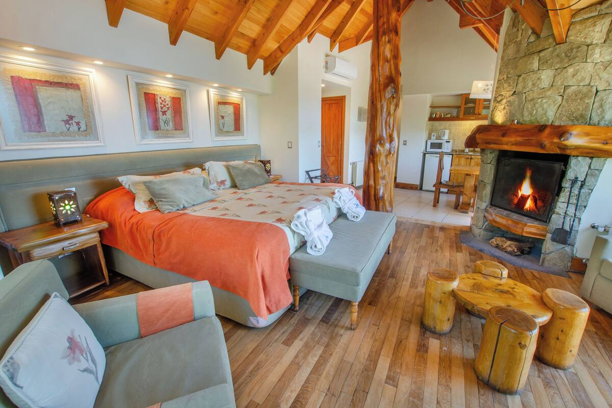 Un dormitorio acogedor con una cama, un banco de madera y una chimenea de piedra.