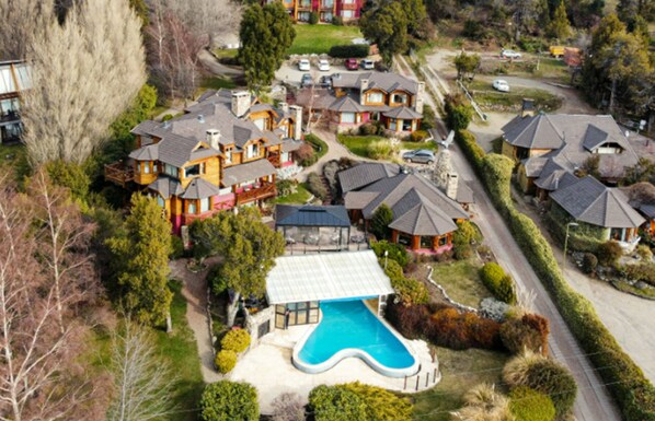 An aerial view of a residential area with multiple houses, a swimming pool, and a well-maintained garden. - Nido del Condor Hotel & Spa (San Carlos de Bariloche)
